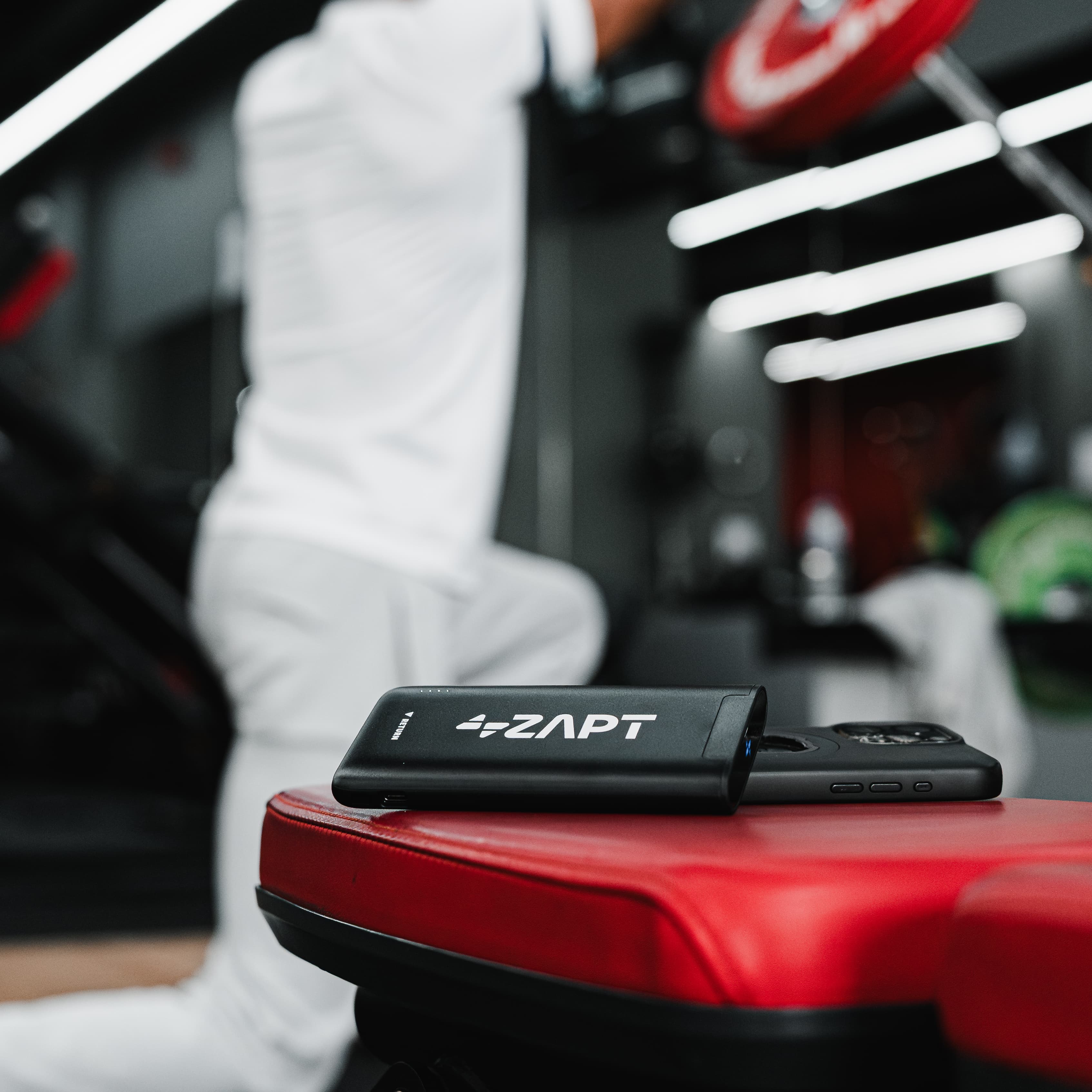 ZAPT-branded powerbank charging a phone on a Snap Fitness gym bench